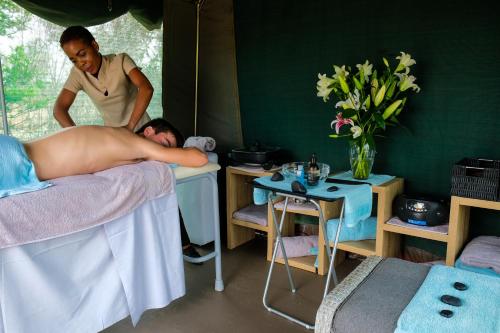 曼耶雷蒂野生动物园Honeyguide Tented Safari Camps - Mantobeni的男人躺在与女人同居的房间里床上