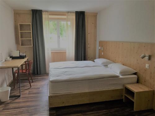 马洛亚Maloja Kulm Hotel的一间卧室配有一张床、一张书桌和一个窗户。