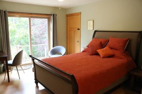 FernwoodFive Elements Lodge B&B with Outdoor Spa的一间卧室设有一张红色大床和窗户