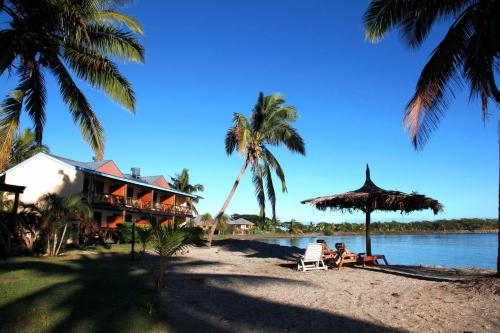 南迪斐济俱乐部度假酒店的棕榈树和椅子上的人在海滩上的房子