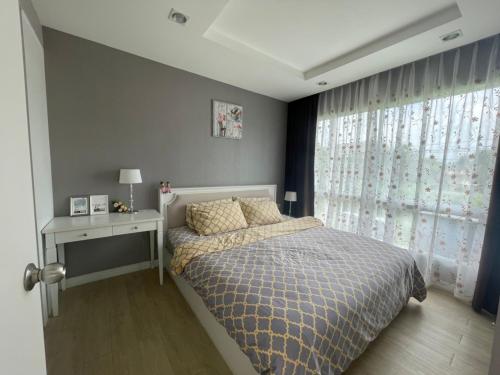 邦盛Exclusive Garden View 1 bedroom suite @Patio Bangsaen的一间卧室配有一张床、一张桌子和一个窗户。