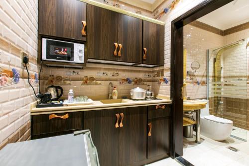 吉达Lambert ApartHotel的厨房配有木制橱柜、水槽和淋浴。