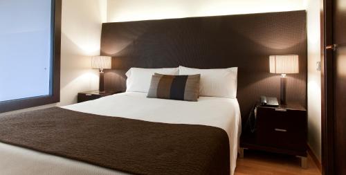 巴塞罗那巴塞罗那参议公寓式酒店的一间卧室配有一张带两盏灯的大型白色床。