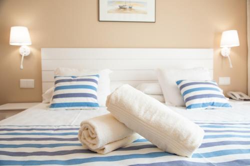 卡里拉Hotel Dwo Les Palmeres的一张带白色毛巾和枕头的床