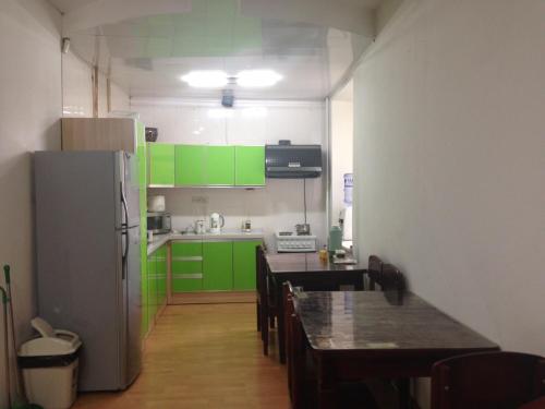 乌兰巴托阳光之路蒙古之旅旅舍的厨房配有绿色橱柜、桌子和冰箱。