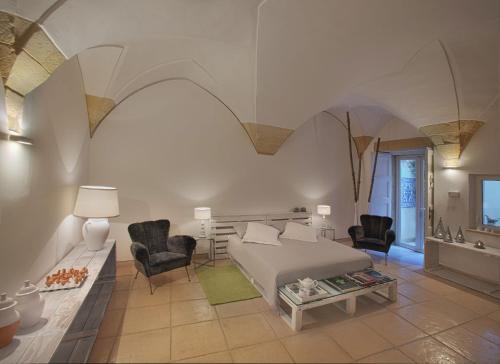 莱切Corte dei Romiti Apartment的一间卧室配有一张床、两把椅子和一张桌子