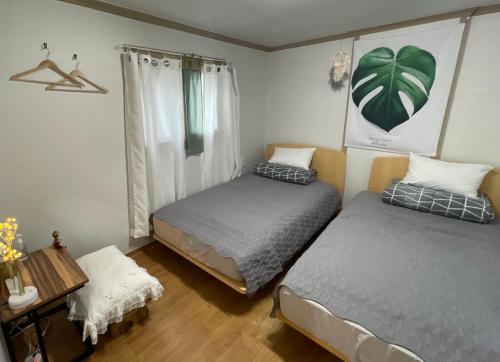 江陵市Saesori Guesthouse的一间卧室配有两张床和一张桌子