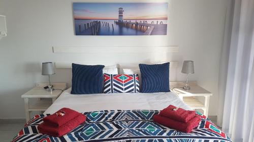 杰弗里湾OCEAN VIEW GUEST HOUSE的一间卧室配有一张带红色枕头的床和一座灯塔。