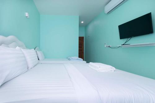 南府Lomluang hostel&hotel的卧室配有白色的床,墙上配有电视