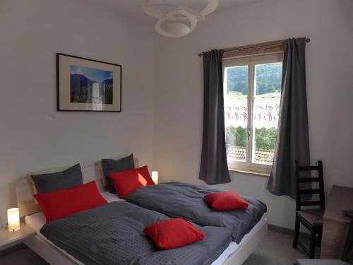 Glovelier格尔餐厅及酒店的一间卧室配有一张带红色枕头的床和一扇窗户