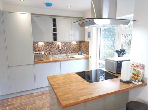 班戈Spectacular 4 Bedroom Sea View Residential Home的厨房配有白色橱柜和木制台面