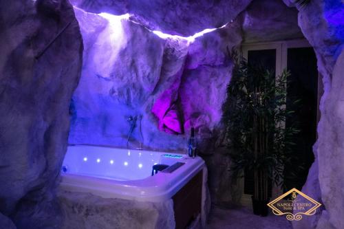 那不勒斯Napoli Centro Suite e Spa的紫色浴室,在岩石墙上设有浴缸