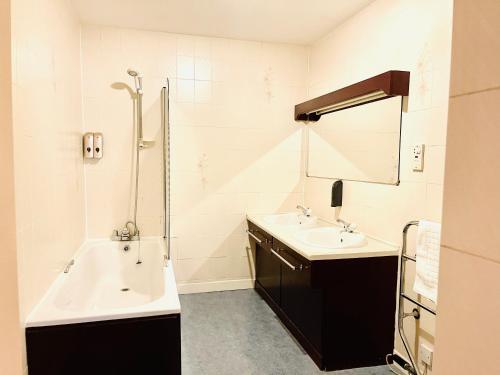 珀斯The Lovat Hotel的浴室配有2个盥洗盆、浴缸和淋浴。
