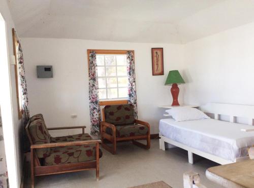 Saint Joseph休闲避风港海滩小屋旅馆的卧室配有床、椅子和窗户。