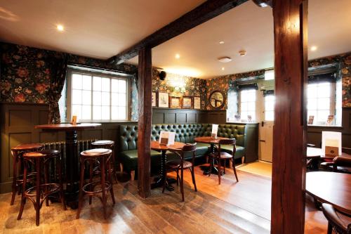赫尔姆斯利The Black Swan - The Inn Collection Group的餐厅内带绿色桌椅的酒吧