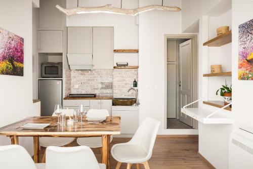 科孚镇Sky Loft Corfu Old Town Apartments的厨房以及带木桌和白色椅子的用餐室。