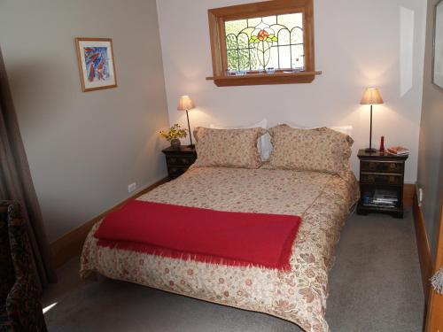 Portobello伊迪山船长酒店的一间卧室配有一张带红色毯子的床