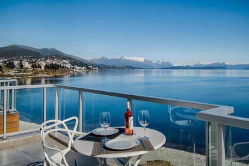 圣卡洛斯-德巴里洛切Bariloche costa del lago Ollagua的俯瞰湖泊的阳台的桌子和两杯酒杯