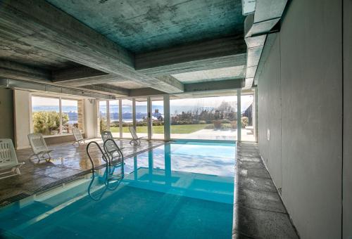 圣卡洛斯-德巴里洛切Bariloche costa del lago Ollagua的房屋内带椅子的游泳池