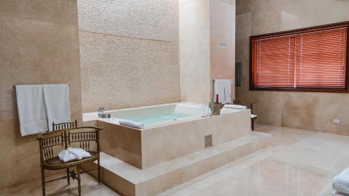 伊察Hotel & Hacienda La Caravedo的带浴缸和椅子的大浴室