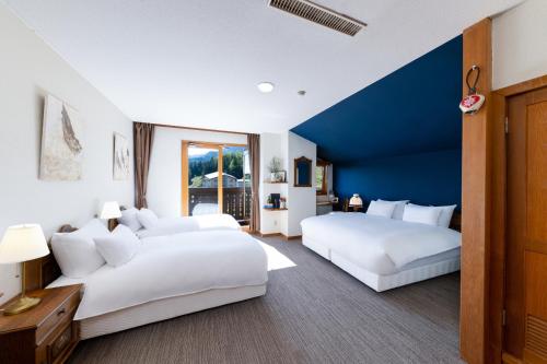 白马村Marillen Hotel by Hakuba Hospitality Group的蓝色墙壁的客房内配有2张白色的床