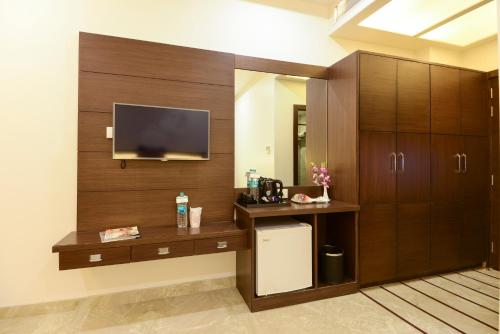 阿格拉阿莱维特酒店的客房设有木制橱柜和墙上的电视。