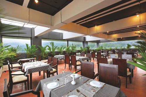提喀迪Holiday Vista Luxury Hotel and Spa, Thekkady的餐厅设有桌椅和窗户。