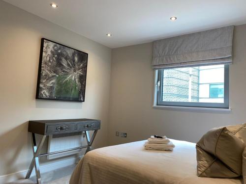 卡迪夫Exclusive Cardiff City Centre Apartment的一间卧室配有一张床、一张桌子和一个窗户。