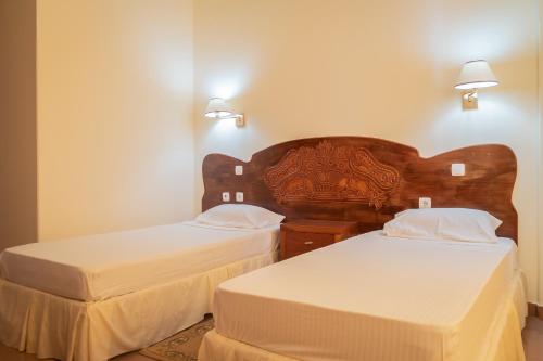 Assomada宇宙住宅小区酒店的配有白色床单的酒店客房内的两张床