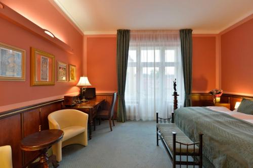 布拉格布拉格老城哈斯塔尔酒店的配有一张床、一张书桌和一扇窗户的酒店客房