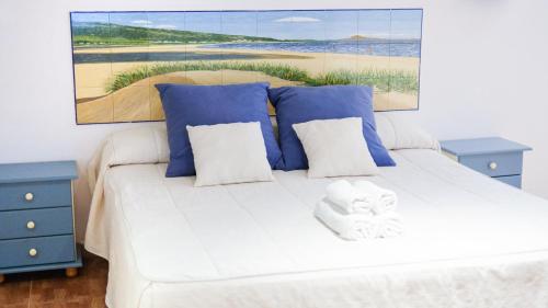 塔里法拉托雷酒店的一间卧室配有白色的床、蓝色的桌子和绘画作品