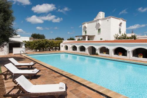 莫诺波利马塞里亚伊尔梅洛格拉诺酒店的一座带躺椅的游泳池和一座建筑