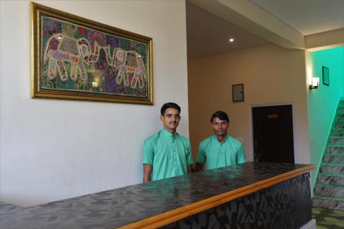 萨瓦伊马多普尔Camp Paridhi Ranthambhore, Homestay的两个人站在一个房间里桌子旁边