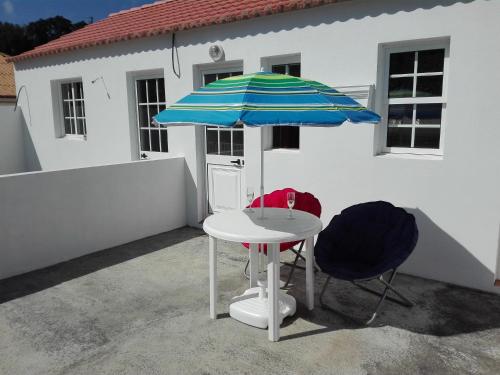TopoMoradia Machado的一张带蓝白雨伞的桌子和两把椅子