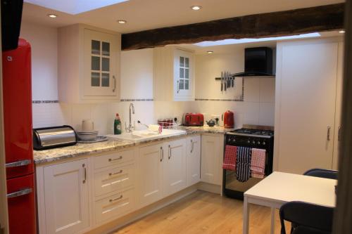 EccleshallEagle House - award winning luxury B&B and Apartment的厨房配有白色橱柜和红色冰箱