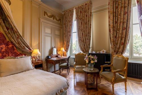 里昂巴亚德贝尔库尔酒店的一间卧室配有一张床、两把椅子和一张书桌