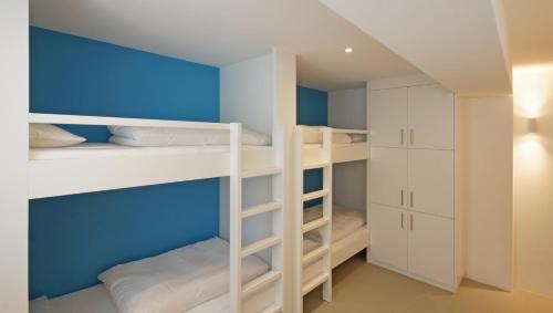 阿彭策尔Alte Metzg - Hostel的一间设有白色双层床和蓝色墙壁的客房