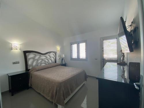 马斯帕洛马斯Bungalow Playa del Aguila的一间卧室设有一张床、一台电视和窗户。