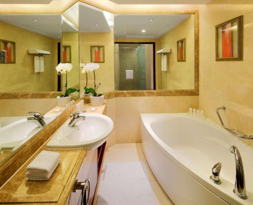 上海上海新世界丽笙大酒店的浴室设有2个水槽、浴缸和镜子