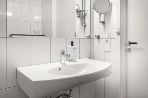 林雪平斯堪迪克林雪平瓦斯特酒店的白色的浴室设有水槽和镜子