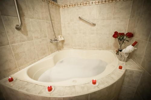 普诺德安马斯庄园广场酒店的浴室内设有带红色蜡烛的浴缸。
