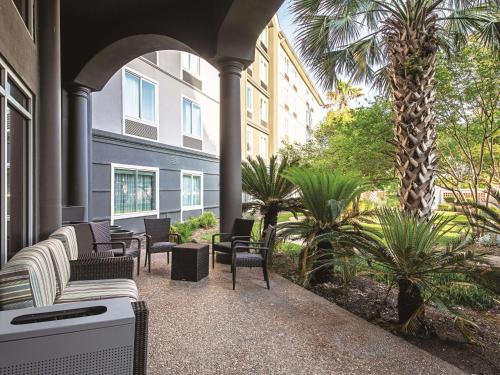 奥斯汀拉金塔套房酒店 - 奥斯汀机场的一个带椅子和棕榈树的庭院和一座建筑