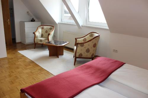 韦尔特湖畔克伦彭多夫柯布旅馆的一间卧室配有两把椅子、一张床和窗户