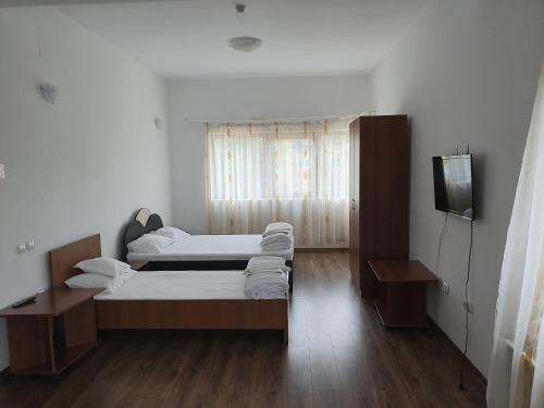 CîmpeniPENSIUNEA ANAIS的客房内设有两张床,铺有木地板,设有窗户。
