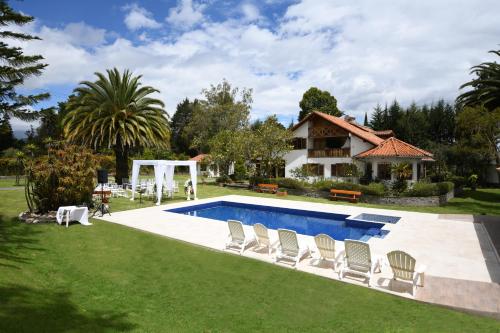 塔巴贝拉Quinta La Constanza的后院设有游泳池、椅子和房屋