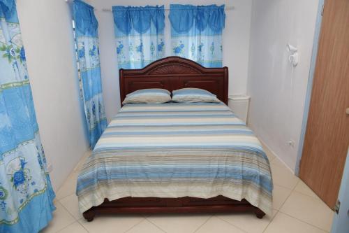 Long PathBreezee的一间小卧室,配有一张带蓝色窗帘的床