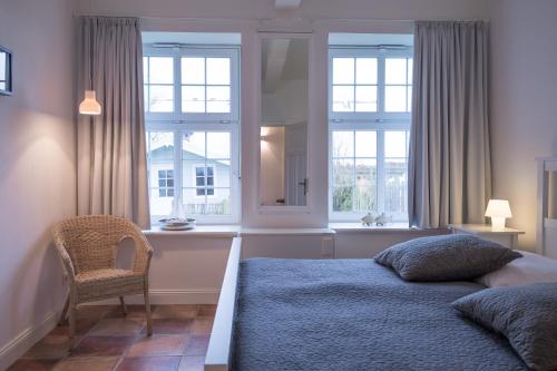 埃默尔斯比尔－霍斯比尔Alte Schule Horsbüll的一间卧室配有一张床、一把椅子和窗户。