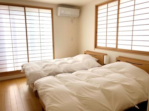 京都ShukuShuku的卧室设有2张白色的床和2扇窗户