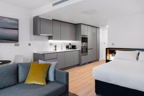 曼彻斯特CitySuites 2 Aparthotel的一间带床和沙发的房间和一间厨房
