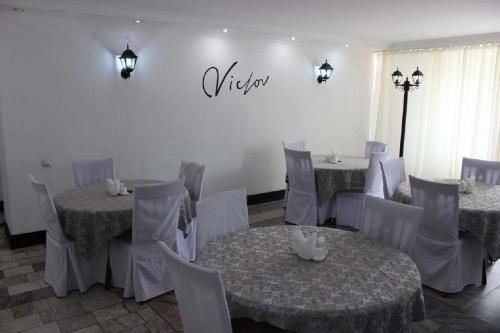 阿克套维多利亚酒店的一间设有桌椅的用餐室和墙上的标志